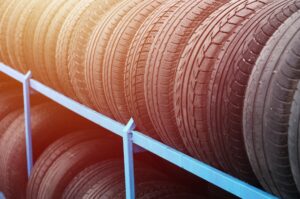 Rack with variety of car tires in automobile store. Many black tires. Tire stack background